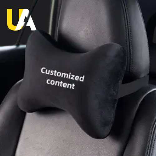 A black velvet car neck pillow strapped to a headrest, with the text 'Customized content' embroidered on it in white. The 'UA' logo in yellow and white is visible in the top left corner.
